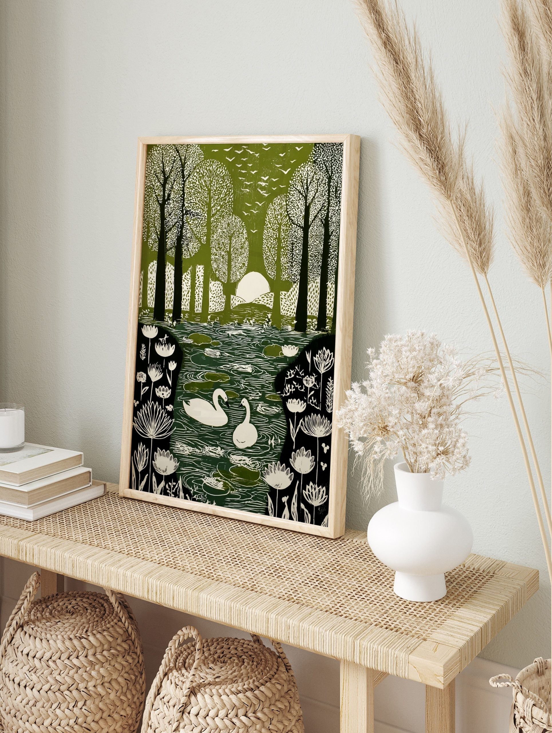 Green and white illustrative print of swans on a pond in a forest with birds flying overhead, in an alternate framed mockup