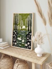 Green and white illustrative print of swans on a pond in a forest with birds flying overhead, in an alternate framed mockup