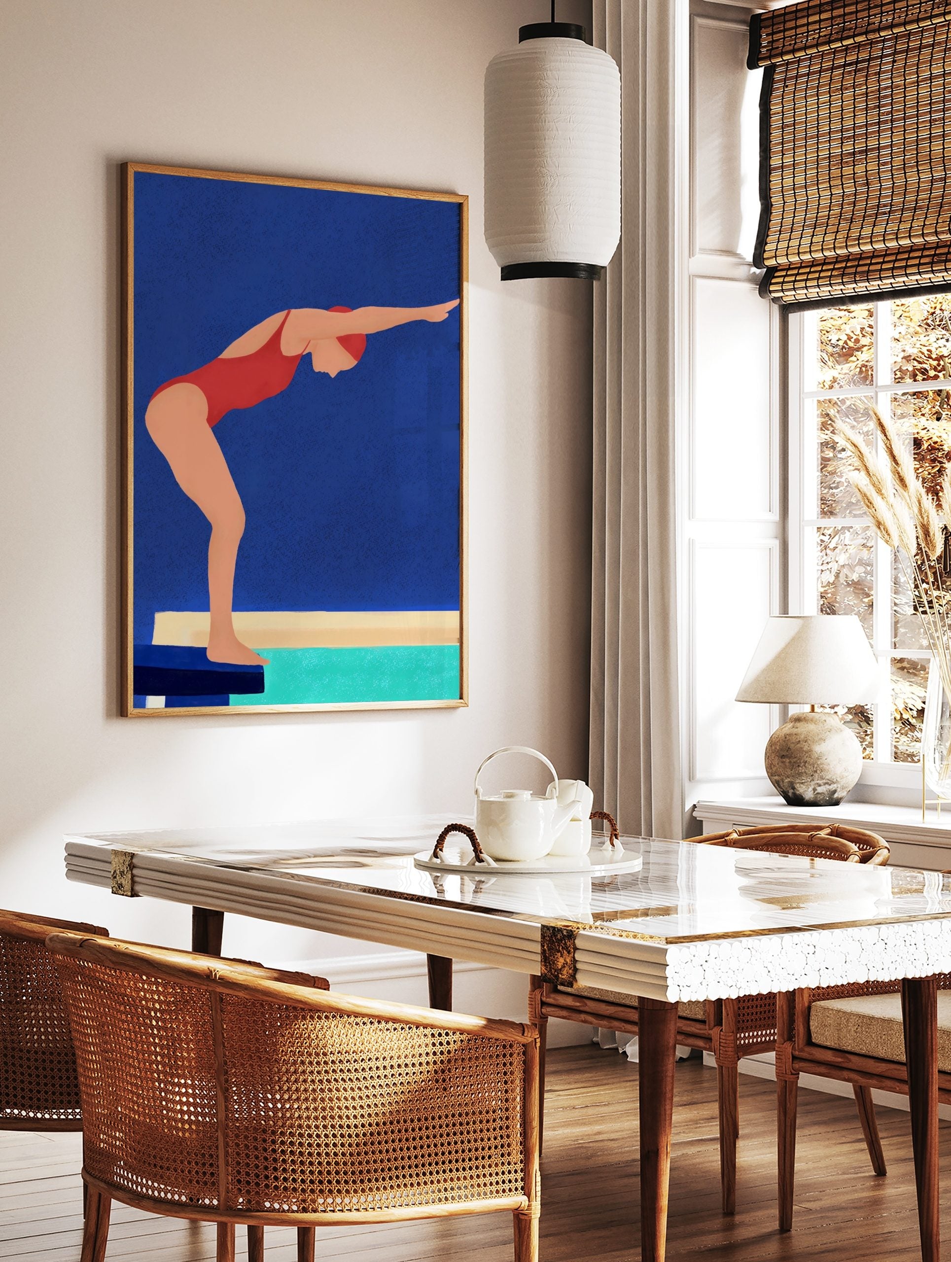 Illustrative wall art of a swimmer in a red swimsuit and cap, poised on a starting block above turquoise water, against a blue background, displayed as the same artwork in a styled poster mockup for home decor