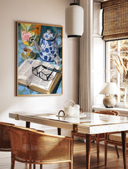 Still life painting with blue floral teapot, teacup, open book with glasses, and a vibrant floral vase. - Image 3