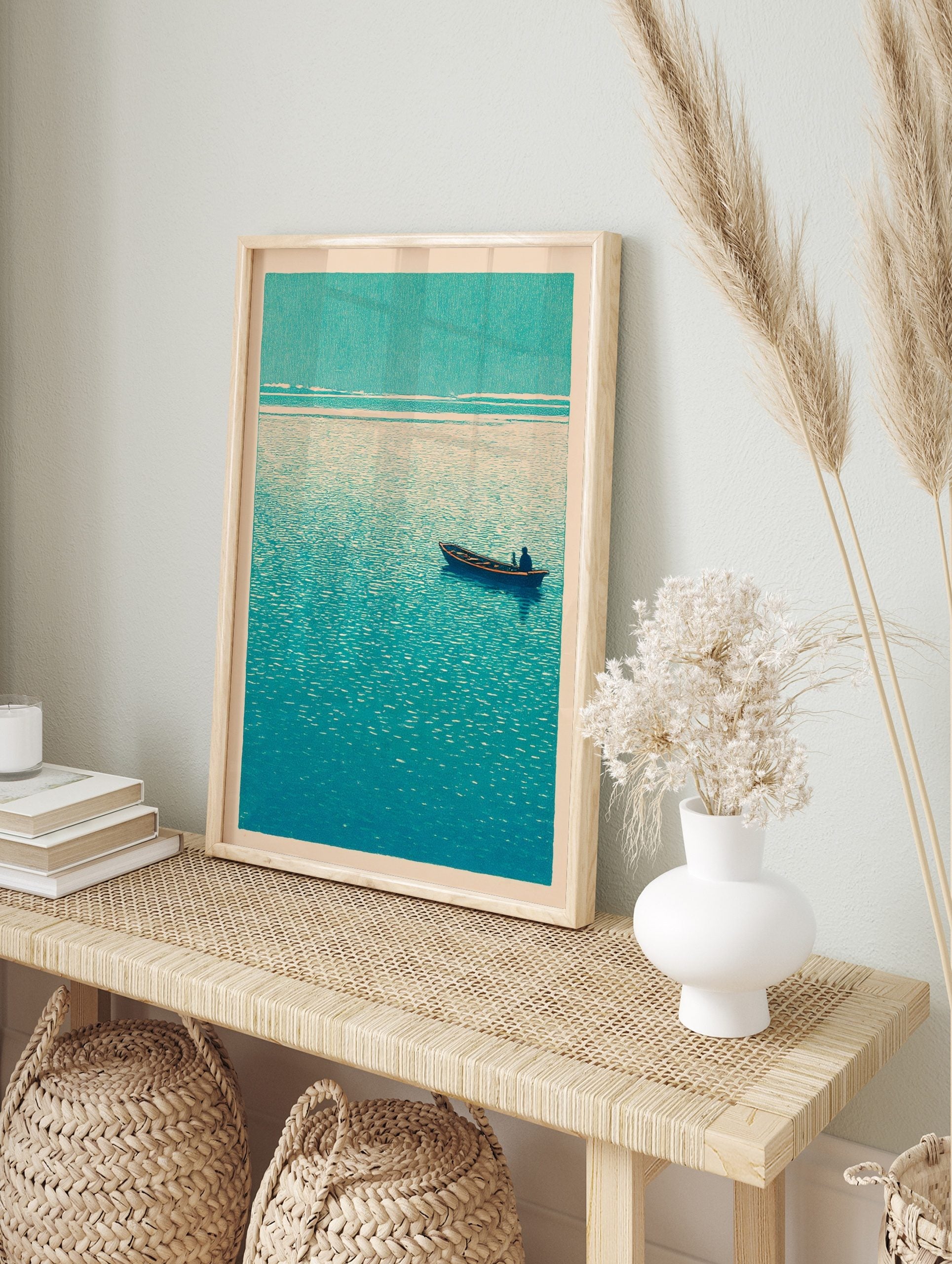 Minimalist teal boat print with a single figure on calm, textured water under a light sky, in an alternate framed mockup