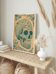 Teal ornate sugar skull illustration with floral patterns and decorative vines on a tan paper, in an alternate framed mockup