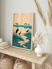Teal heron wetland art print with three birds, tall grasses, and stylised swirling water, in an alternate framed mockup