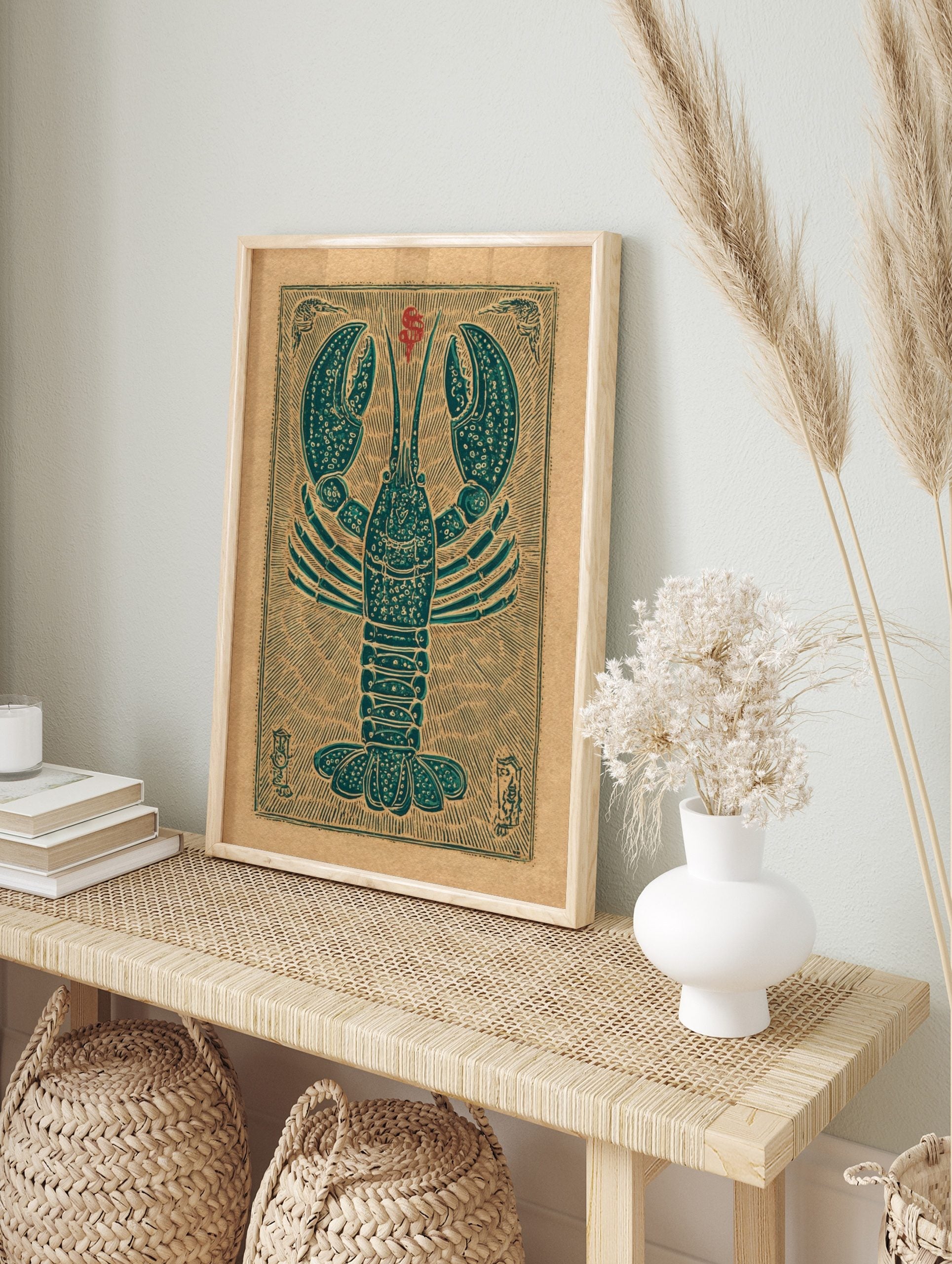 Teal lobster woodcut style art print on a tan background with red symbol and decorative border, in an alternate framed mockup