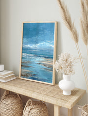 Textured blue seascape painting with white ocean waves and sandy beach under a cloudy sky, in an alternate framed mockup