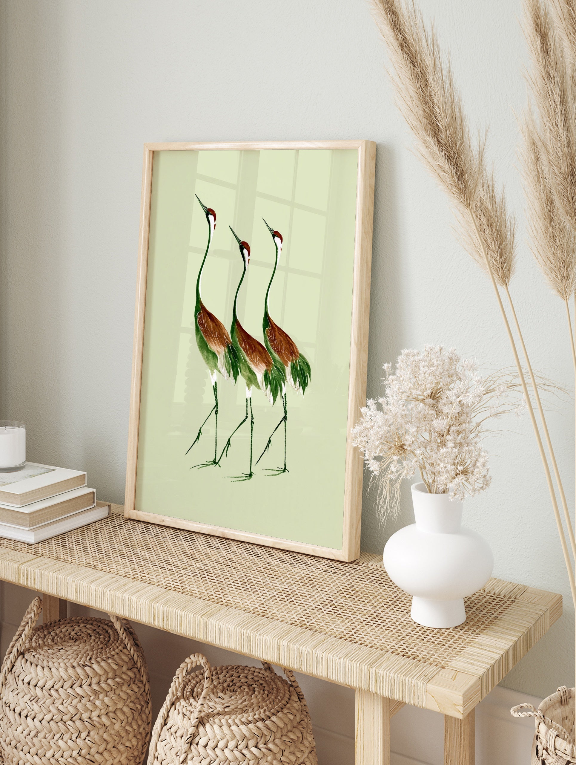 Three cranes illustration in green and russet brown on a light green background, botanical, in an alternate framed mockup