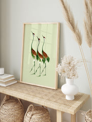Three cranes illustration in green and russet brown on a light green background, botanical, in an alternate framed mockup