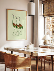 Three cranes illustration in green and russet brown on a light green background, botanical bird, in a styled room mockup