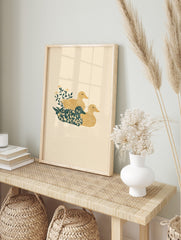 Illustrative print of three ducks, one floral teal, two golden yellow, with green leaves and, in an alternate framed mockup