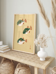 Three pufferfish in Japanese woodblock style with green bodies and orange fins on a cream, in an alternate framed mockup