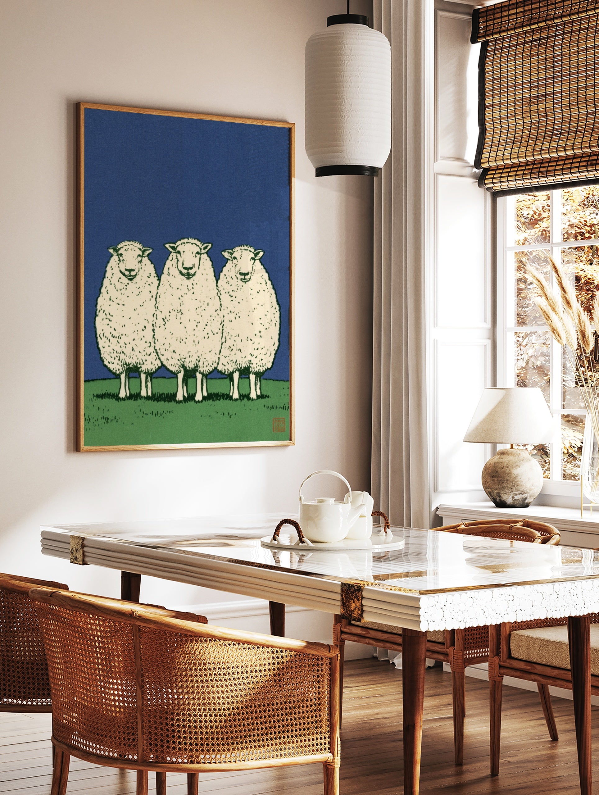 Three sheep standing in a row on a green field against a solid blue sky, illustrative art print, in a styled room mockup