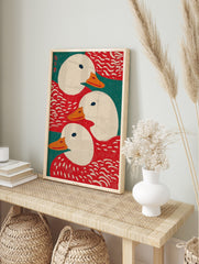 Illustrative art print showing three white ducks with orange beaks against red and teal green, in an alternate framed mockup