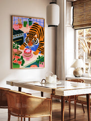 A whimsical illustration of a tiger icing a strawberry cake in a colourful kitchen with blue tiles, in a styled room mockup