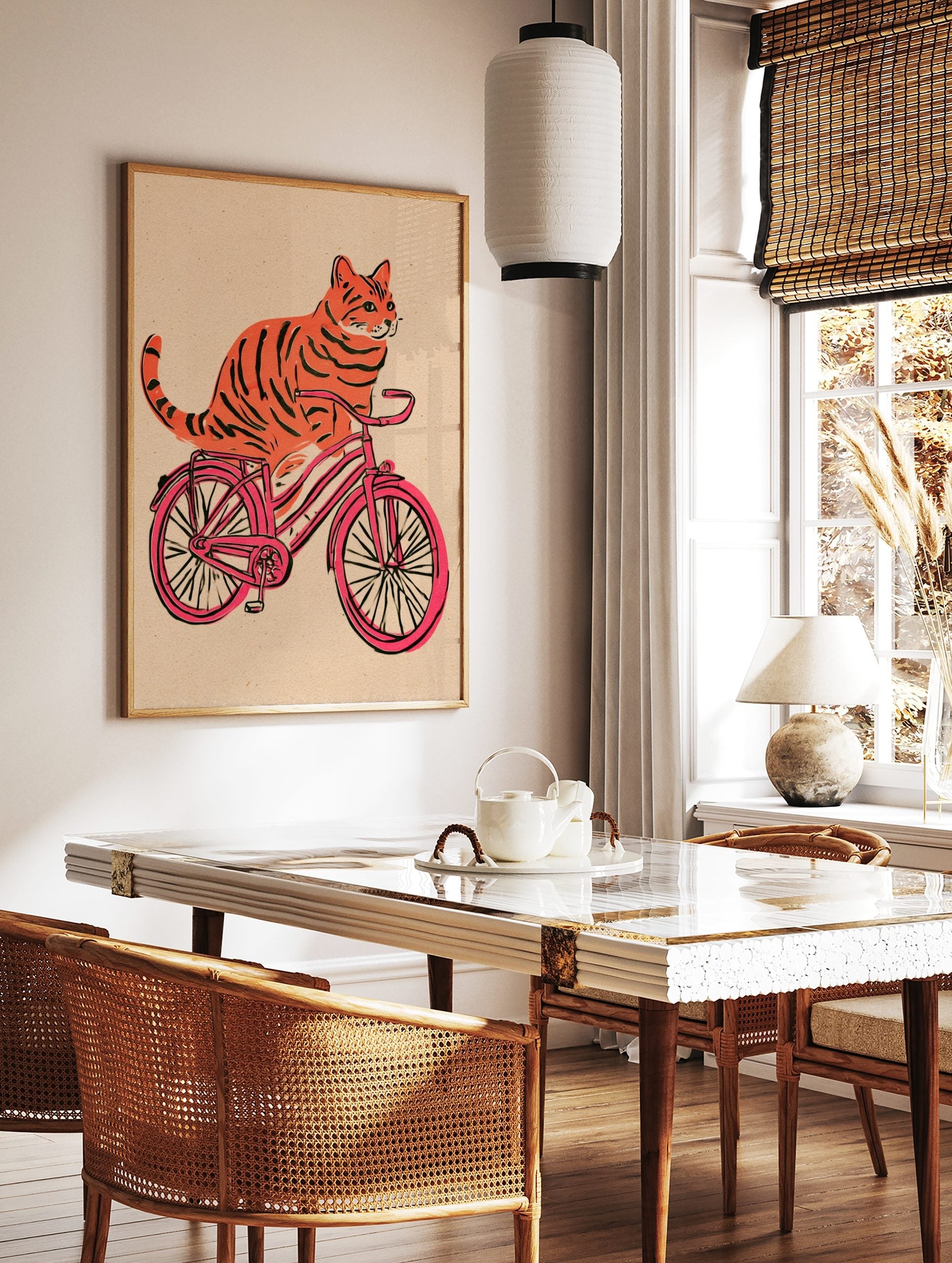 Orange tiger-striped cat riding a pink bicycle illustration on a textured beige background, in a styled room mockup