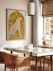 Illustrative golden tiger art print with white stripes and botanical details within an arched frame, in a styled room mockup