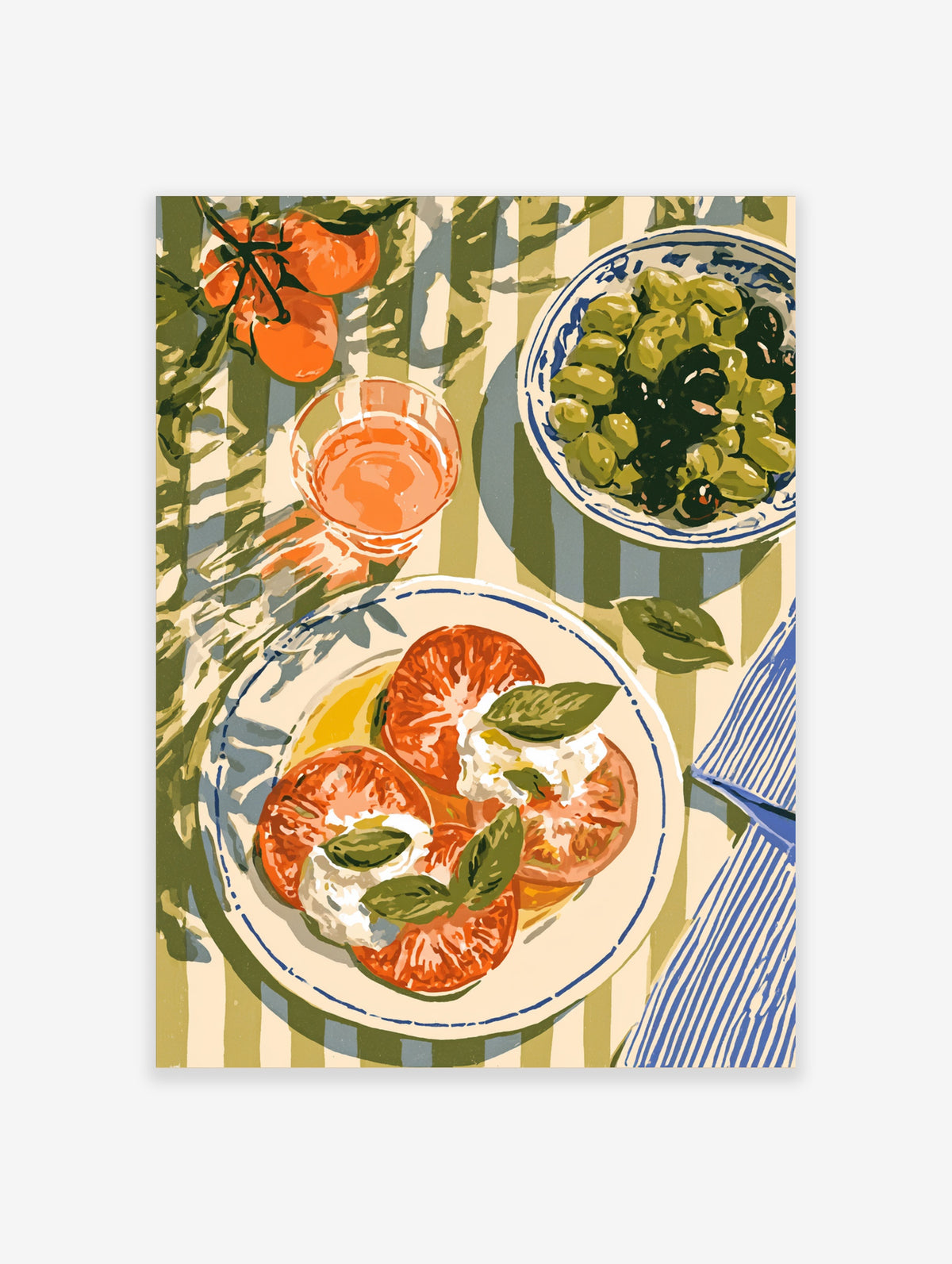 Caprese salad with tomatoes, mozzarella, and basil on a striped tablecloth, with rosé and olives