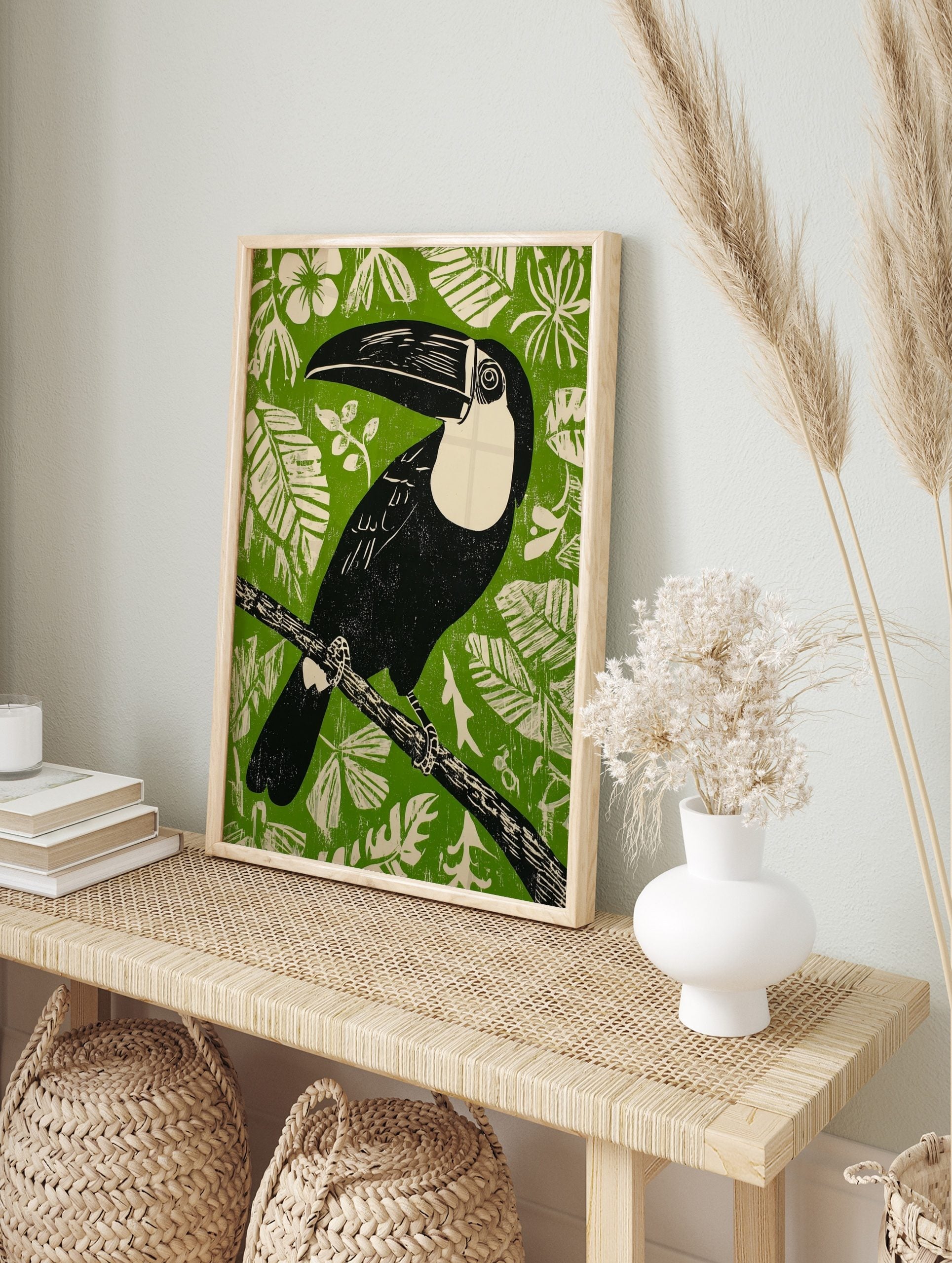 Illustrative black toucan with cream chest and large beak on branch against green background, in an alternate framed mockup