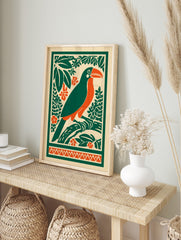 Illustrative toucan bird print with orange beak, green body, tropical leaves, and orange, in an alternate framed mockup