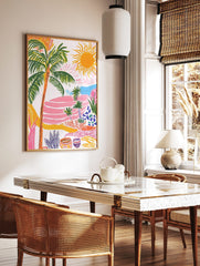 Colourful tropical landscape art print with palm trees, bright sun, pink terraced hills, and blue, in a styled room mockup