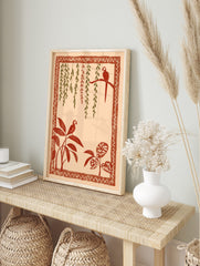 Illustrative tropical wall art with two red parrots, green and red hanging vines, and leafy, in an alternate framed mockup
