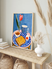 Illustrated breakfast scene with a red tulip, blue striped mug, and toast on a polka-dot, in an alternate framed mockup