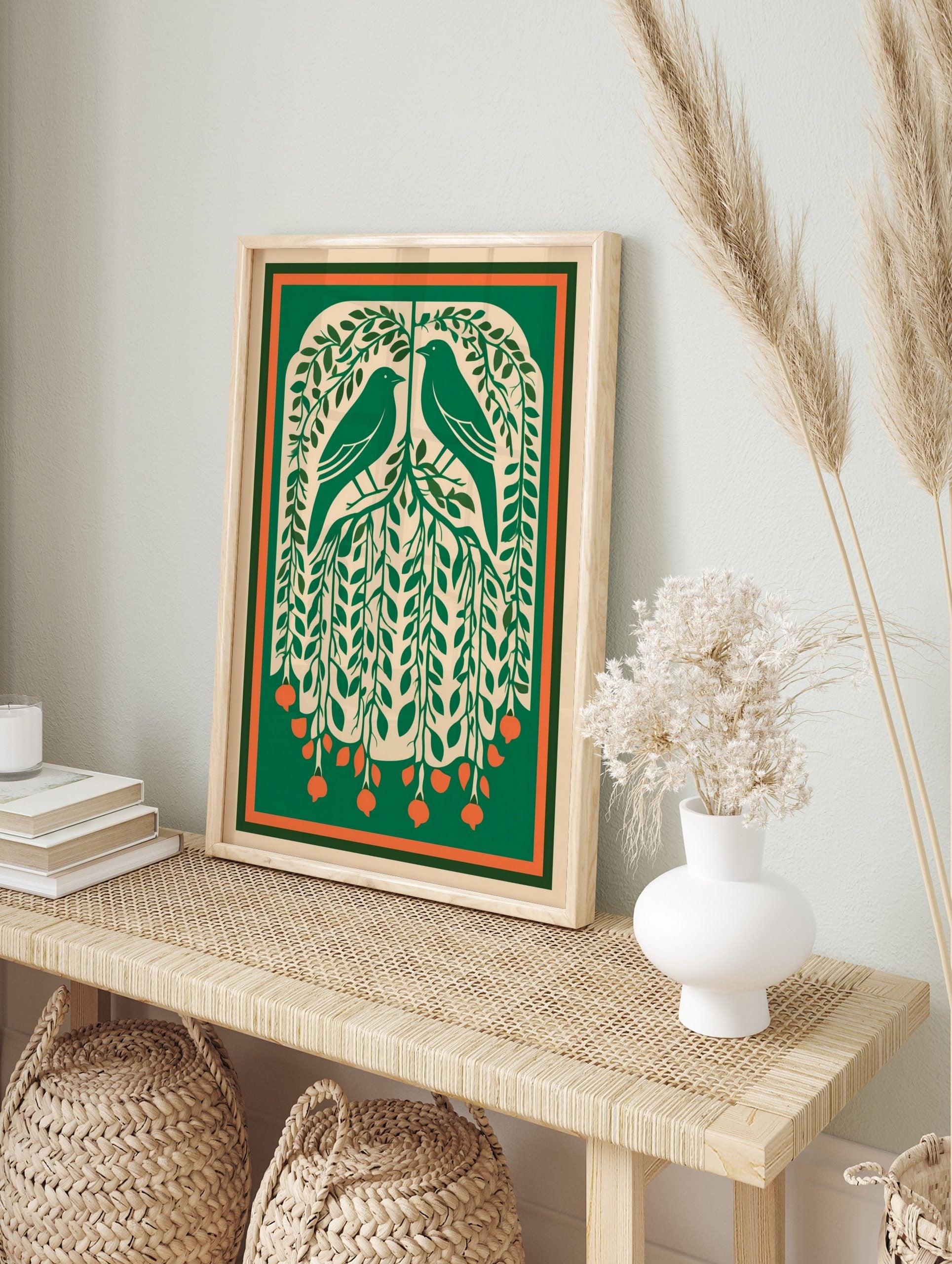 Illustrative green art print of two birds in a leafy tree with orange berries and a, in an alternate framed mockup
