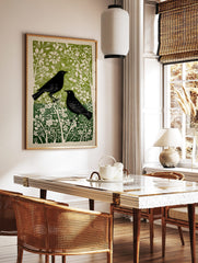 Two black birds with white eyes in a green and white botanical linocut art print, portrait, in a styled room mockup