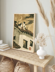 Two cats sitting on a tiled roof looking at a crescent moon, Japanese style illustration art, in an alternate framed mockup