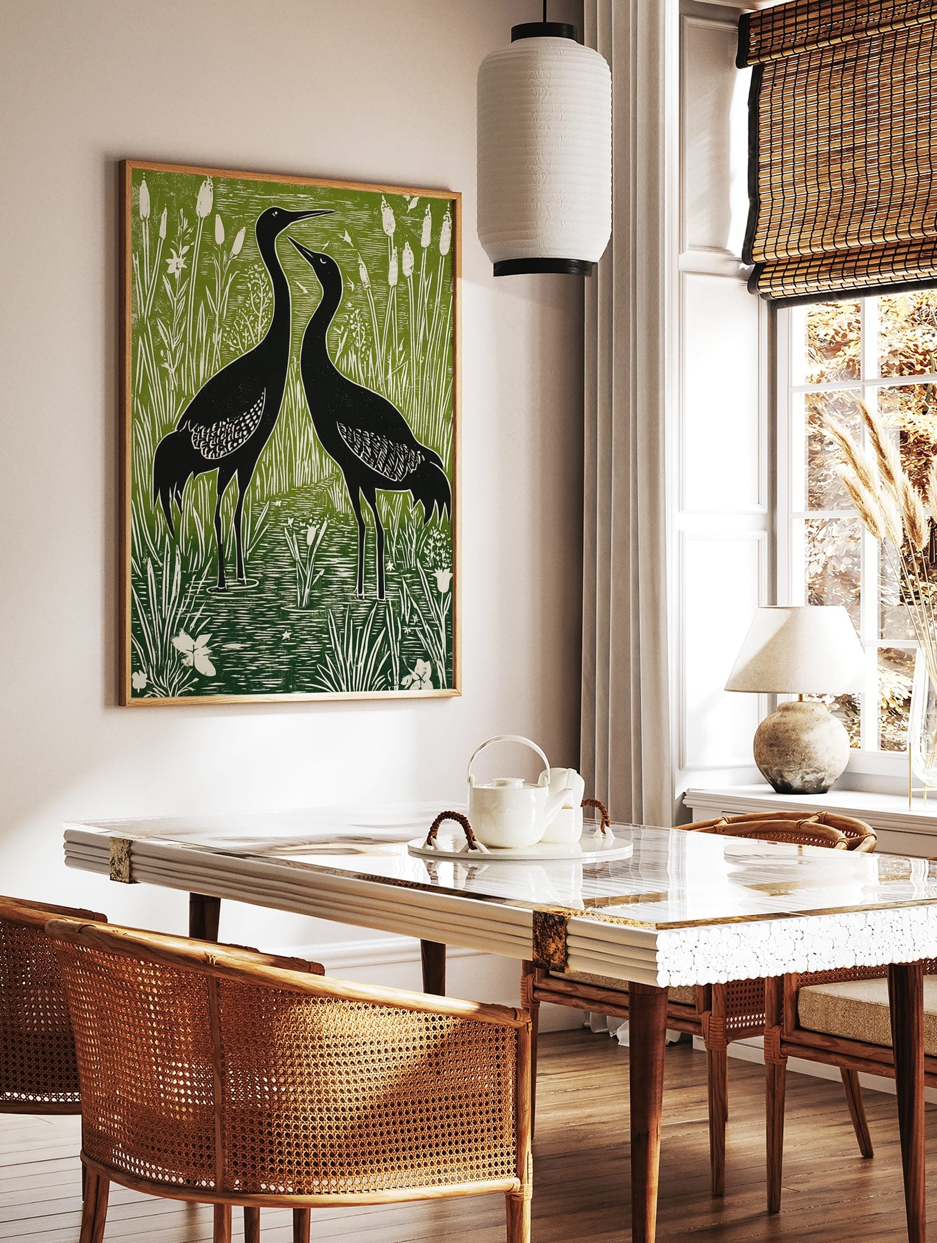 Two black cranes standing in a green and white wetland with tall reeds and cattails, in linocut, in a styled room mockup