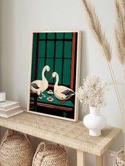 Illustrative wall art of two white geese with red beaks at a green table with cake and a, in an alternate framed mockup