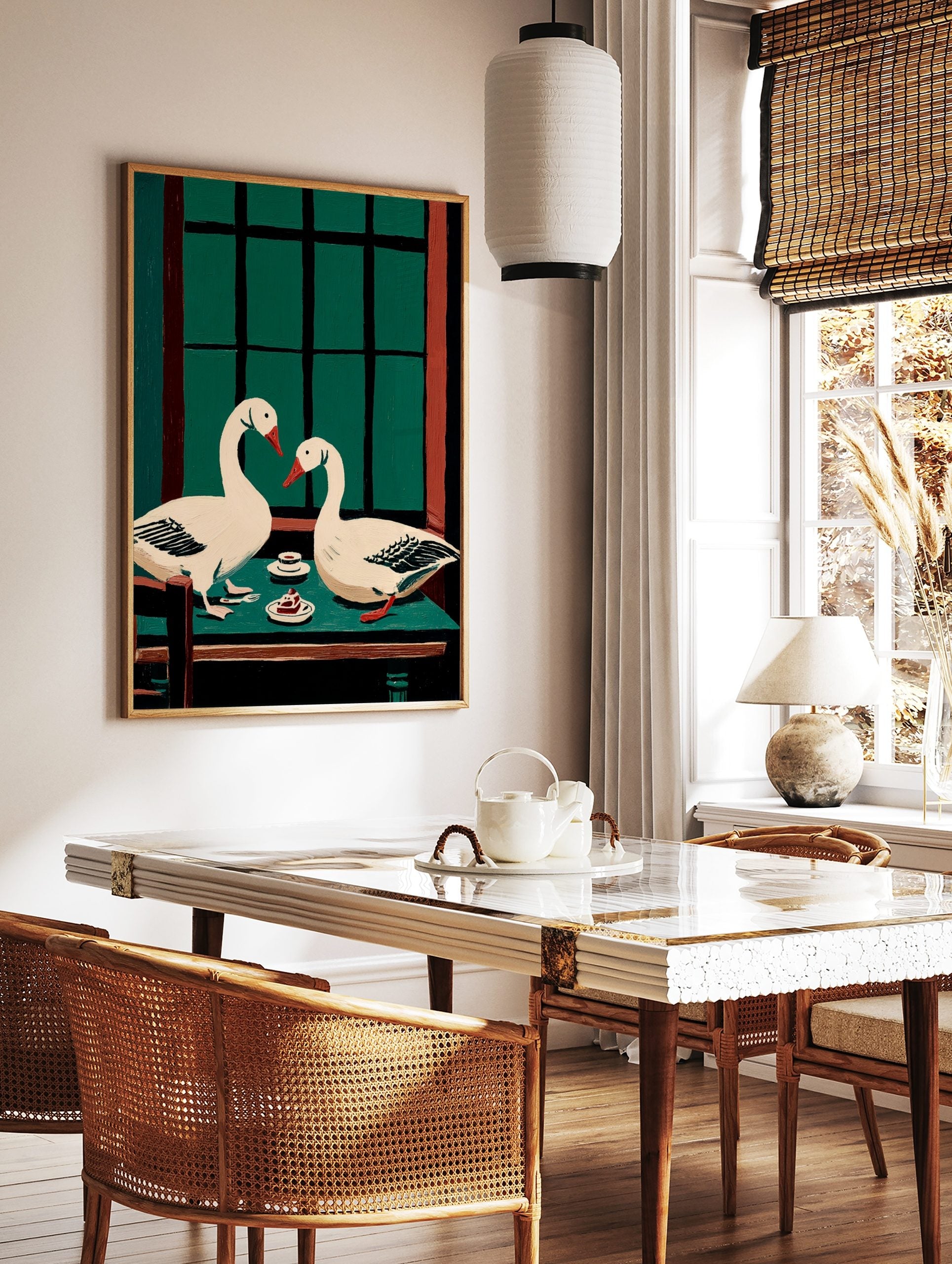 Illustrative wall art of two white geese with red beaks at a green table with cake and a window, in a styled room mockup