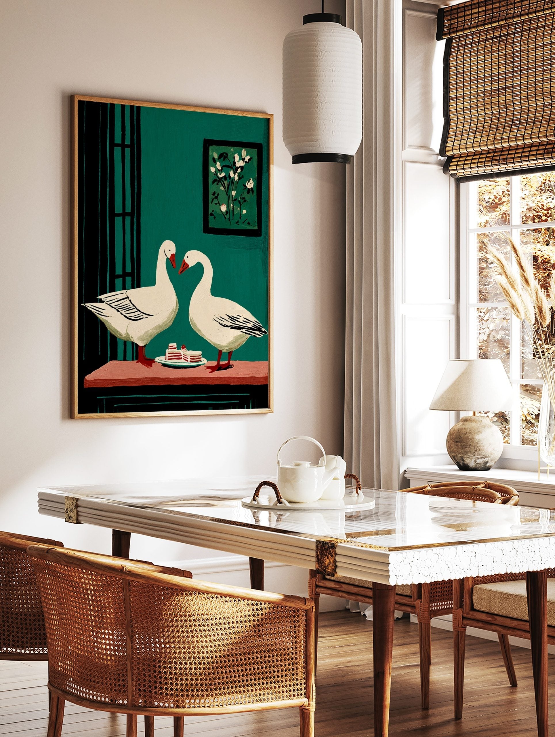 Two white geese with red beaks facing each other over cake slices on a table, against a teal green, in a styled room mockup