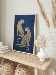 Two golden illustrative leopards with intricate patterns seated on a navy blue background, in an alternate framed mockup