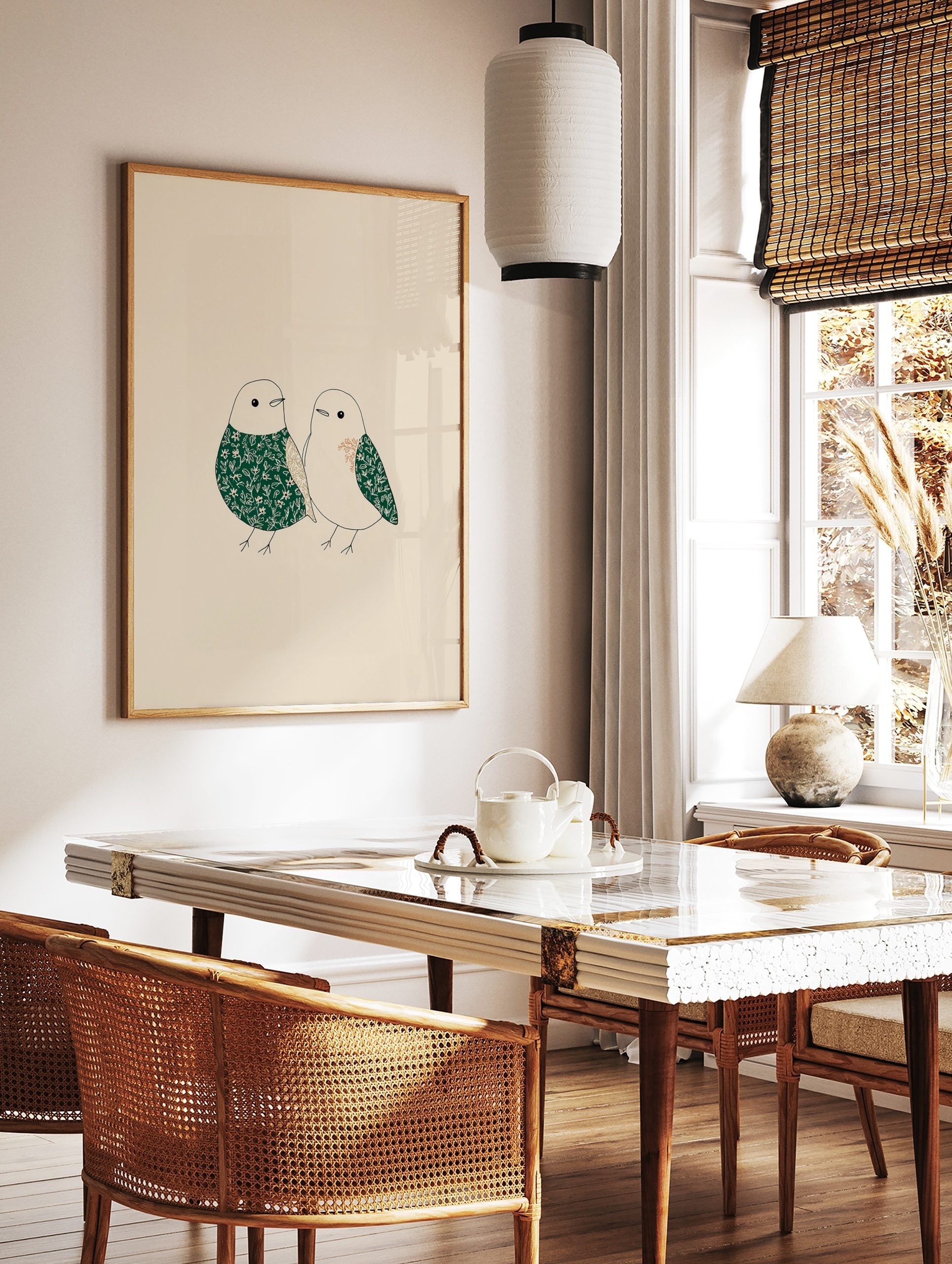 Illustrative art print of two birds with green and beige floral patterns on a light background, in a styled room mockup