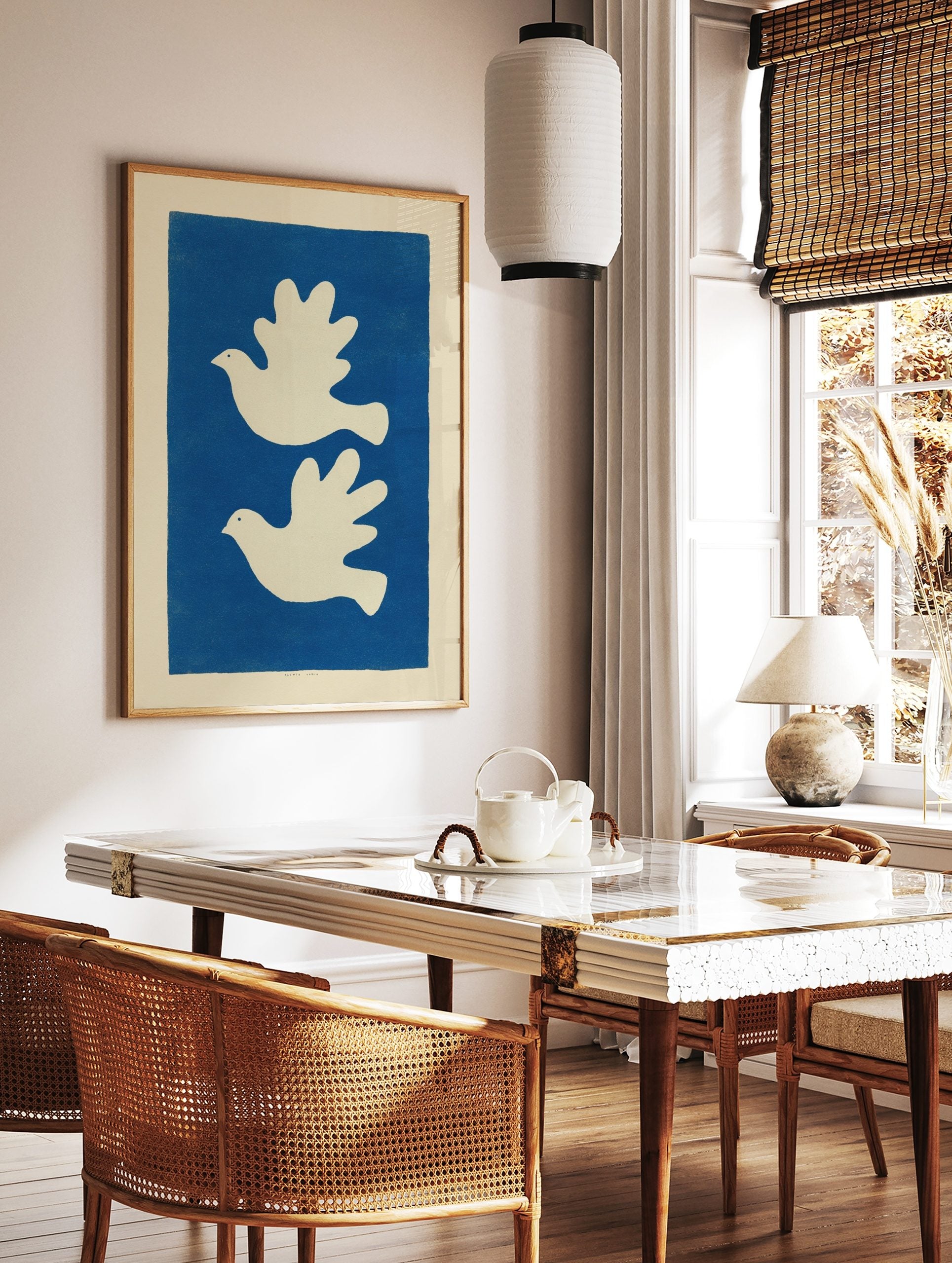 Minimalist art print with two white doves flying left on a solid blue background, in a styled room mockup