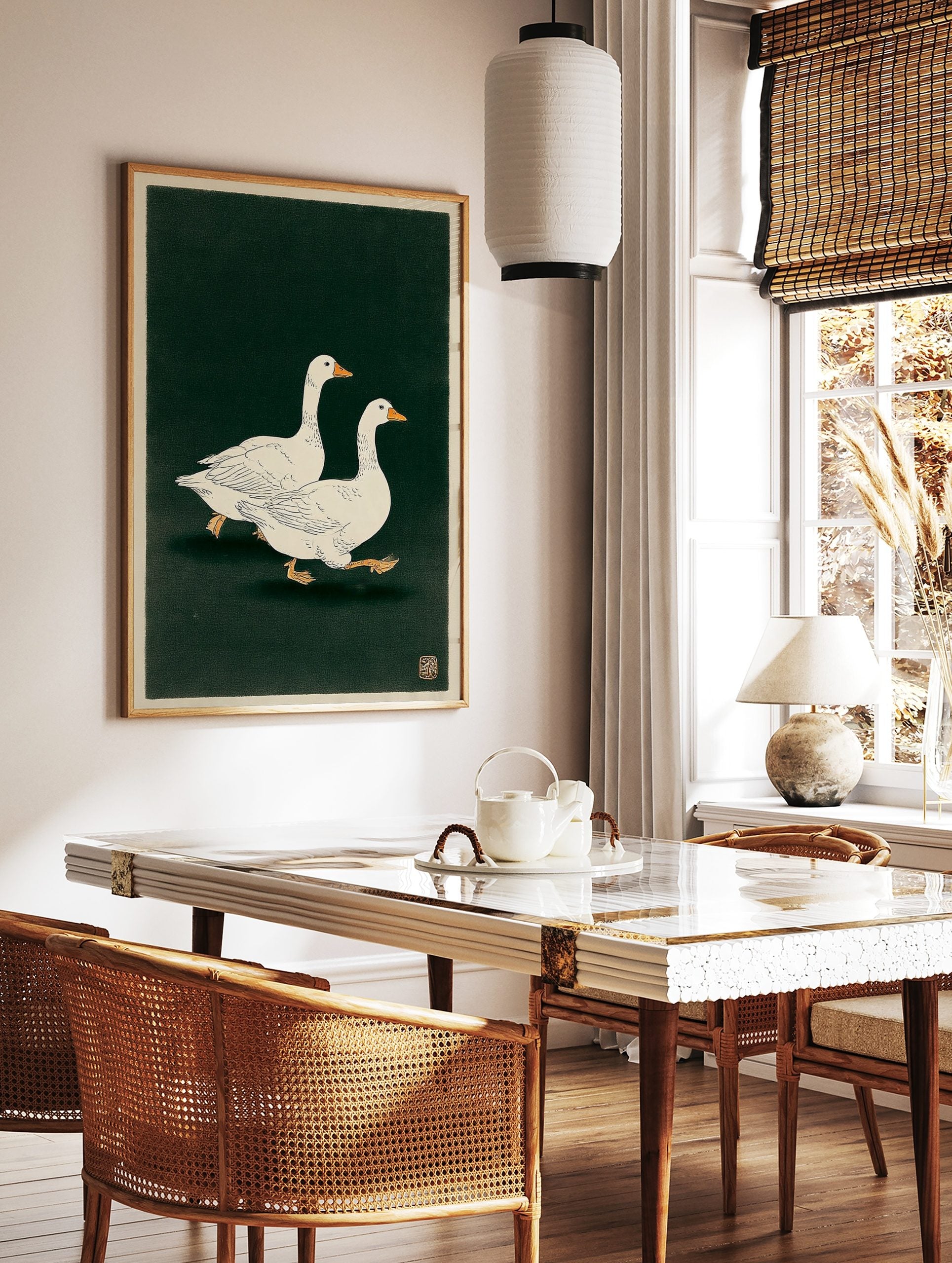 Illustrative print of two white geese with orange beaks walking on a dark green background, in a styled room mockup