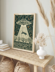 Illustrative woodcut style print of a UFO abducting a striped tiger with a light beam over a, in an alternate framed mockup