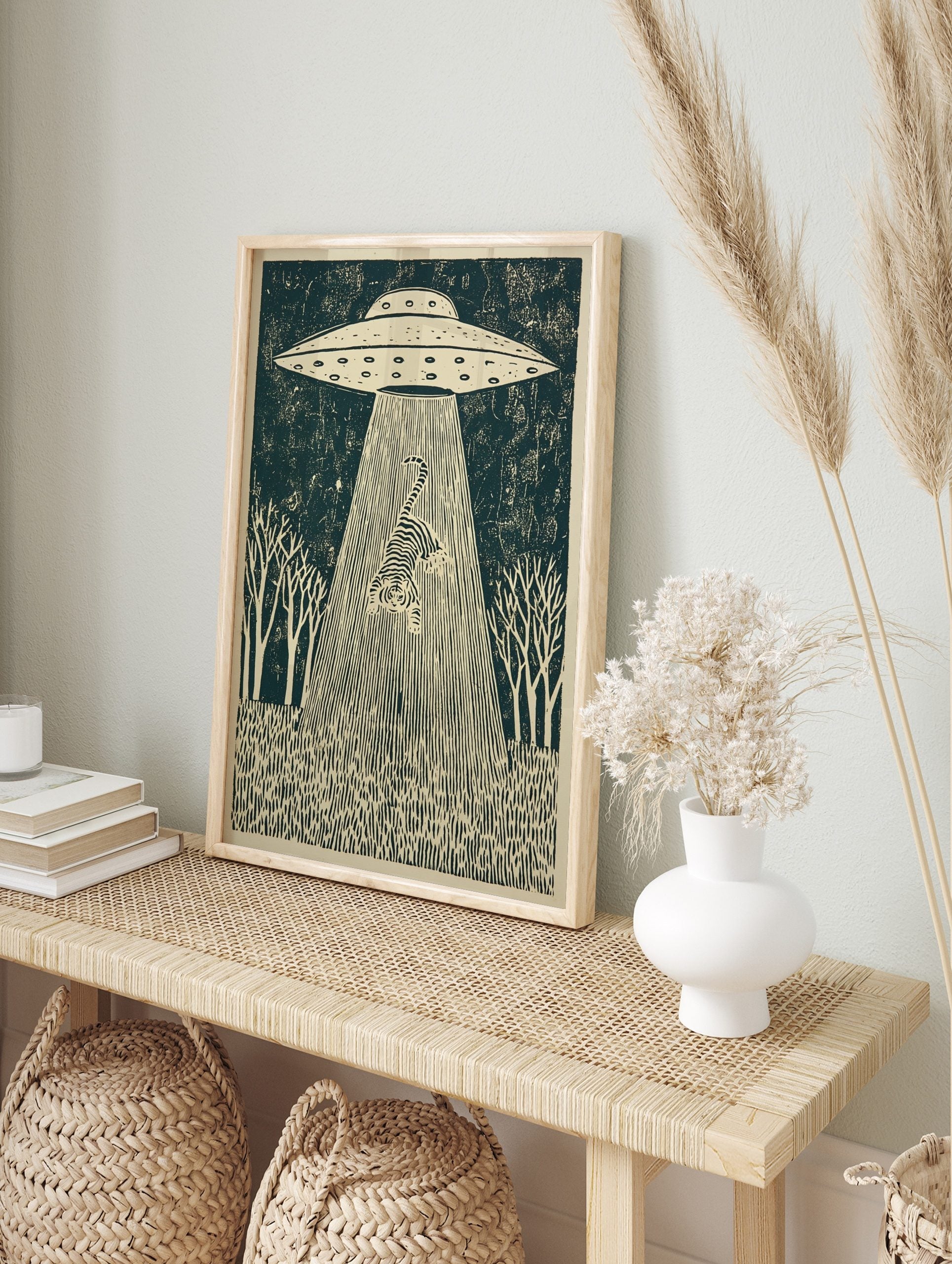 Linocut-style print of a striped tiger being abducted by a UFO's tractor beam, set in a forest, in an alternate framed mockup