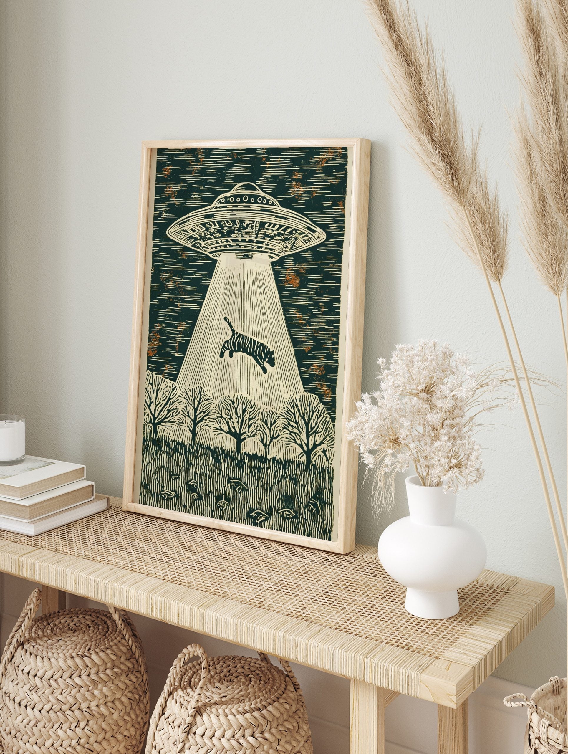 Linocut style wall art of a striped tiger being abducted by a UFO's beam over a forest at, in an alternate framed mockup