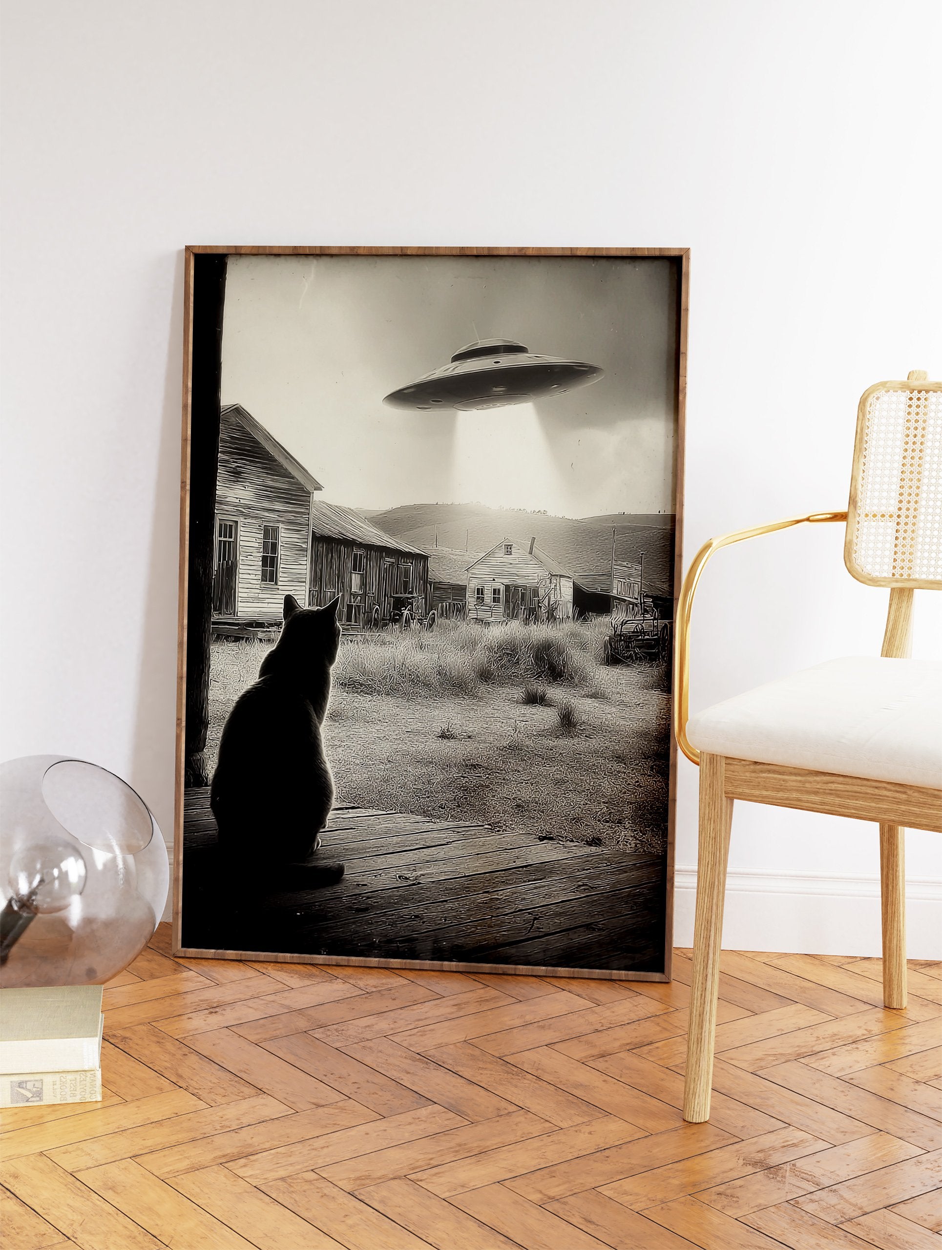 Black and white UFO Cat Wall Art showing a cat on a porch looking at a UFO hovering over old houses in a rural setting. - Image 2