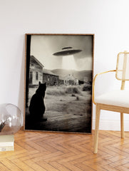 Black and white UFO Cat Wall Art showing a cat on a porch looking at a UFO hovering over old houses in a rural setting. - Image 2
