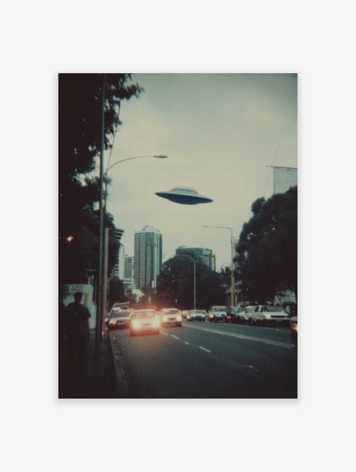 Retro sci-fi print of a UFO flying over a city skyline with cars and buildings at dusk