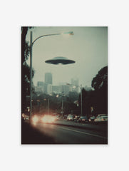 Retro photographic print of a flying saucer hovering over a hazy city street with car headlights and tall buildings