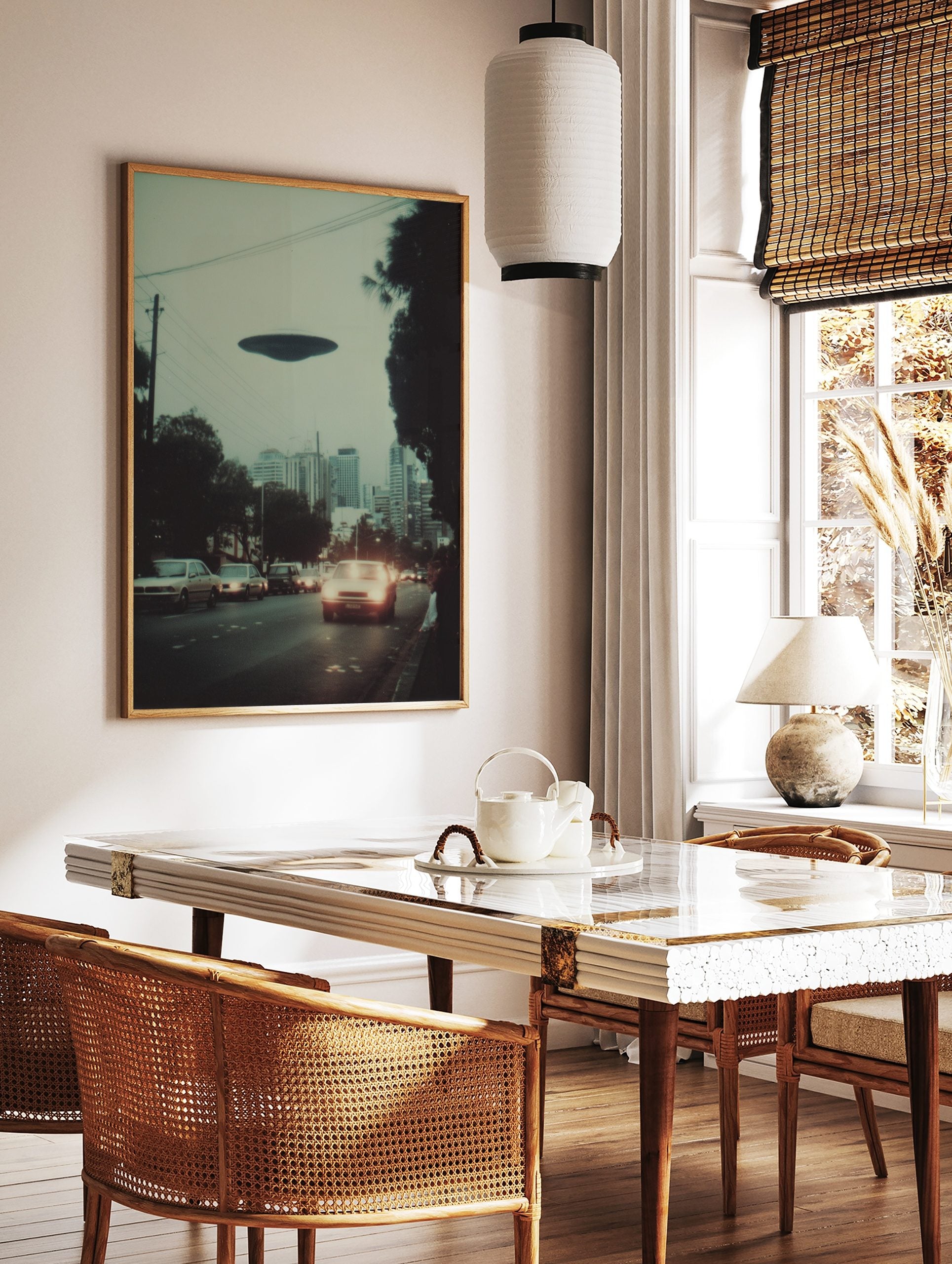 Photographic print of a dark disc-shaped UFO hovering over a city street with cars and buildings at, in a styled room mockup