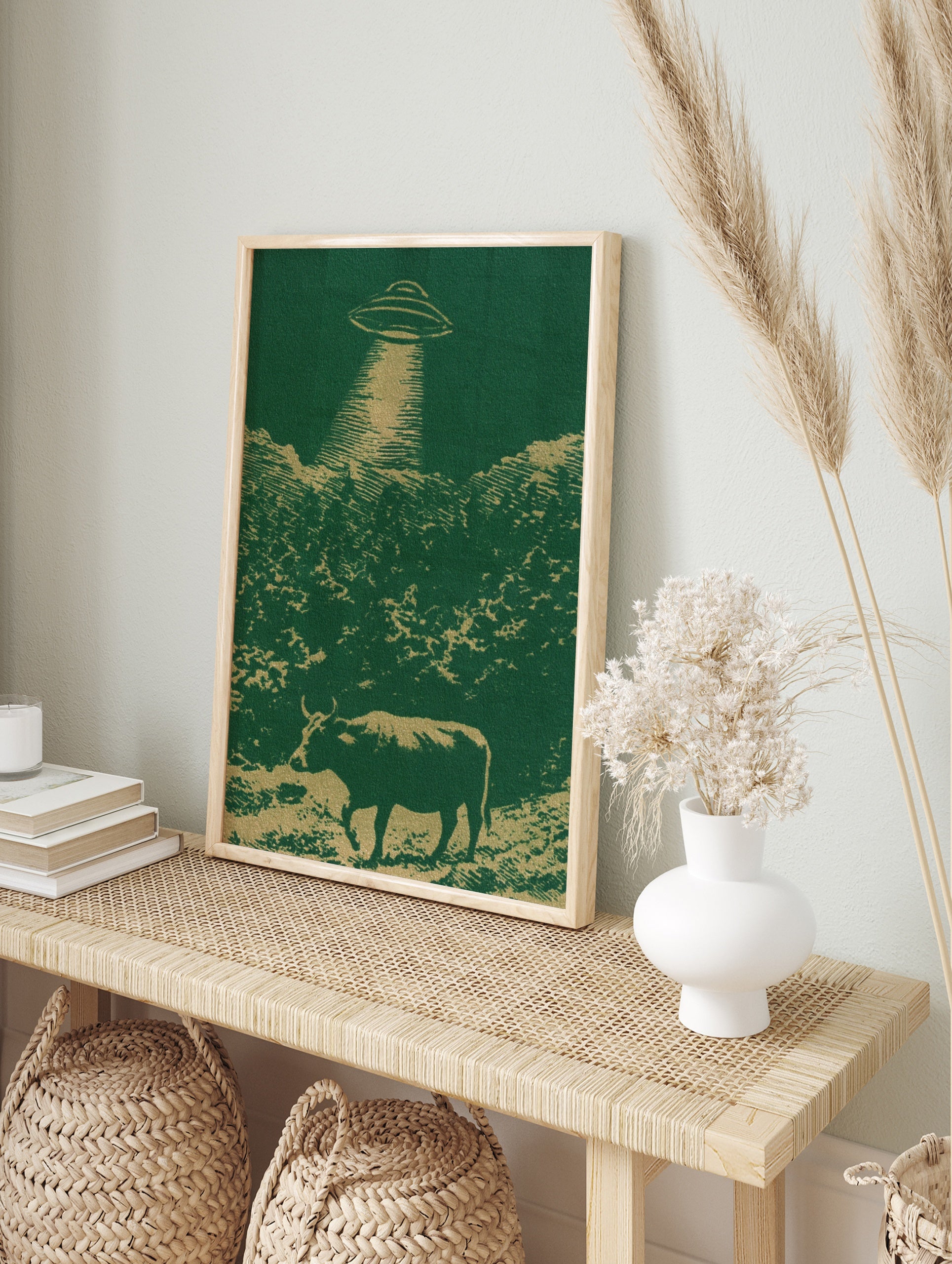 UFO hovering over a cow in a field illustration with green and gold colours, retro-futurist, in an alternate framed mockup