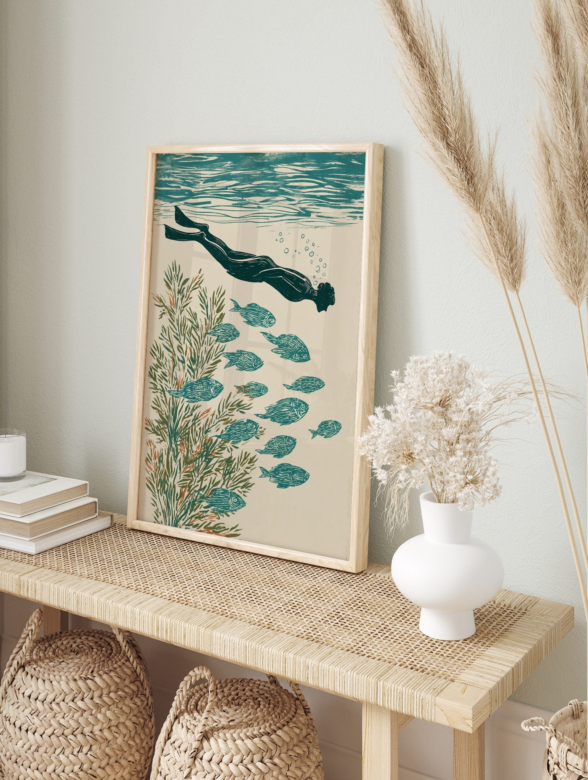 Illustrative print of an underwater swimmer with fins, school of fish, and green seaweed in, in an alternate framed mockup