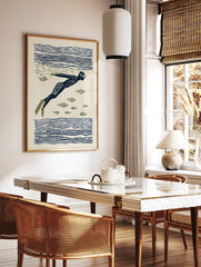 Illustrative print of an underwater swimmer in a dark blue suit and flippers, surrounded by olive, in a styled room mockup