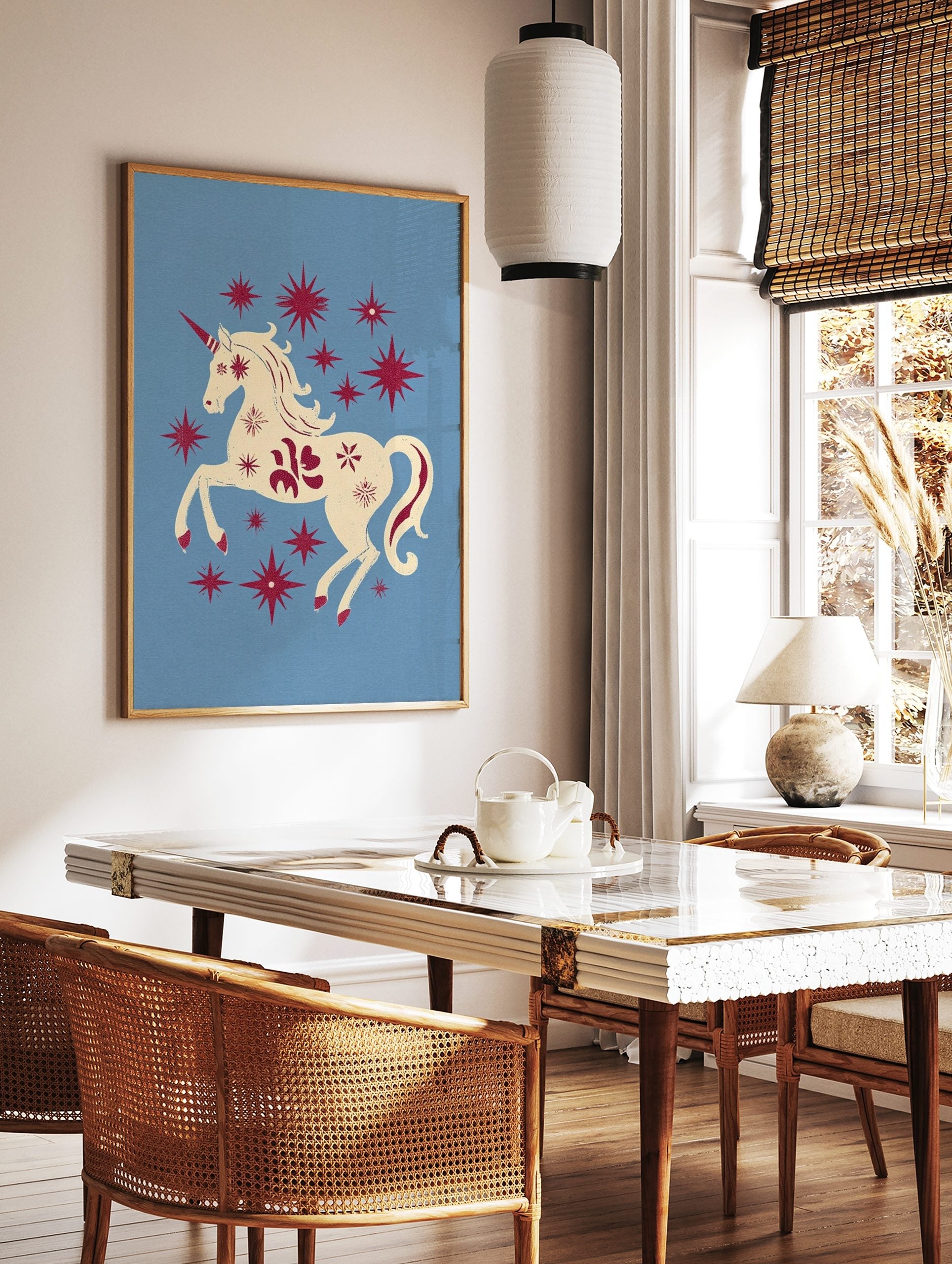 Cream unicorn with red horn and mane prancing among red stars on a light blue background, in a styled room mockup