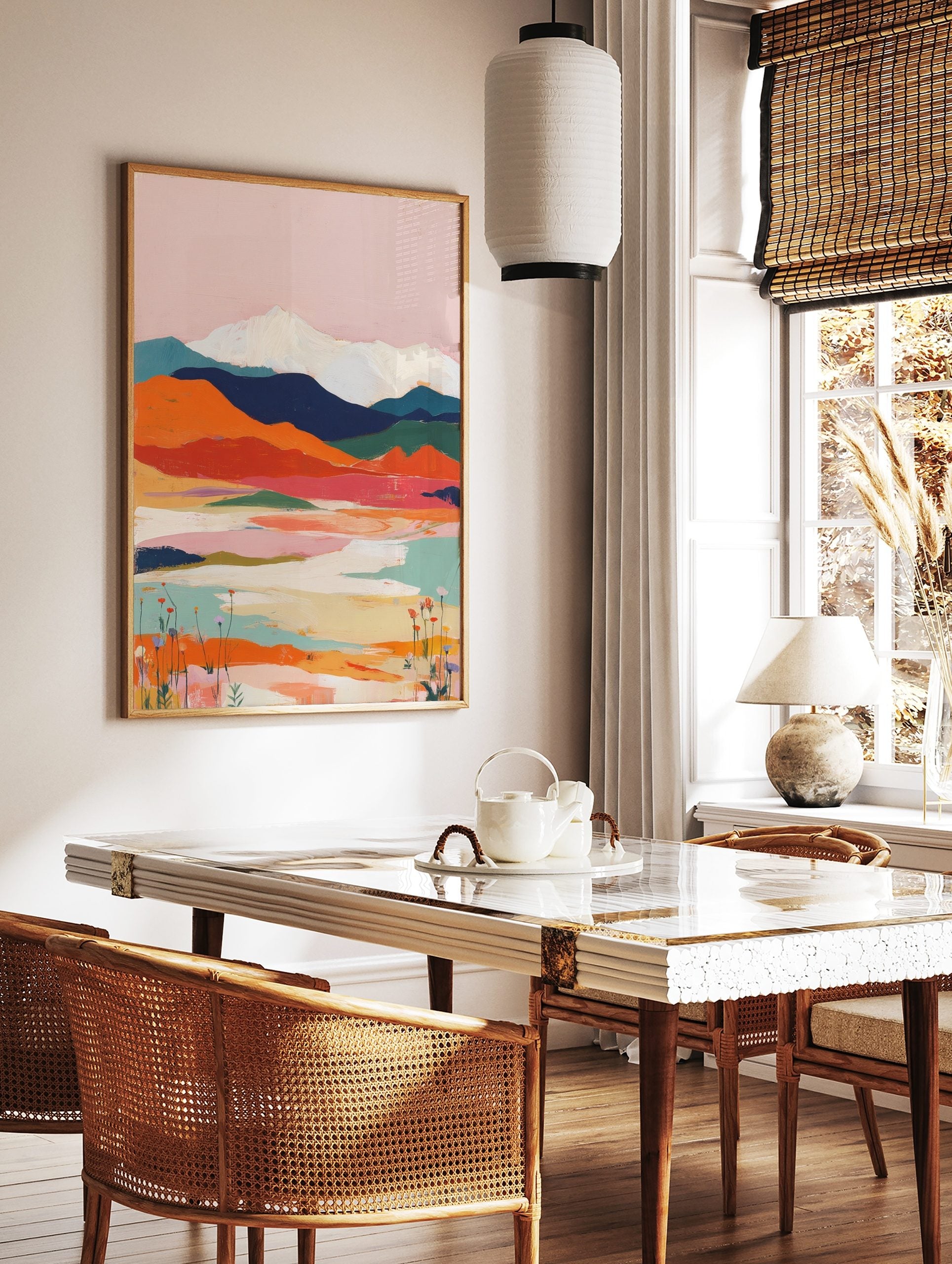 Abstract mountain landscape art print with pink sky, orange hills, blue mountains, and white peaks, in a styled room mockup