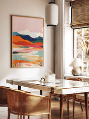 Abstract mountain landscape art print with pink sky, orange hills, blue mountains, and white peaks, in a styled room mockup